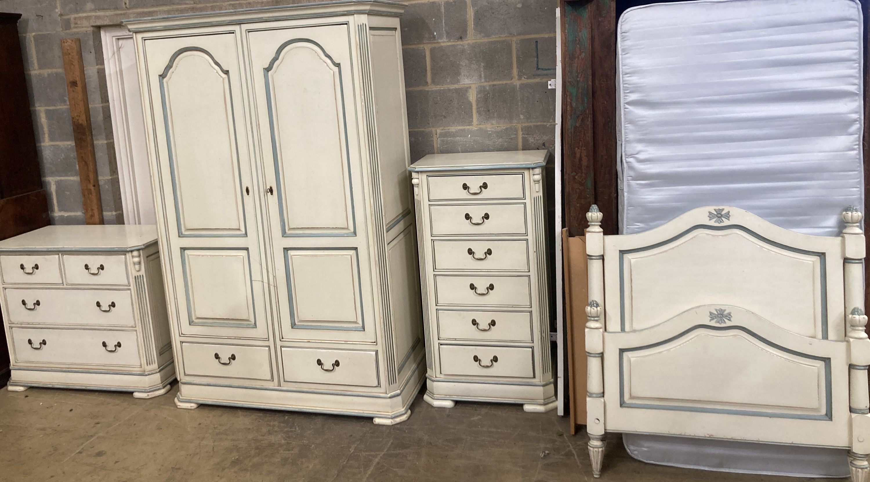 A French provincial style bedroom suite, cream painted, with blue line edging, consisting:- a two door wardrobe, four drawer chest, single bedstead and a tall chest of six drawers, wardrobe W.126cm D.61cm H.202cm